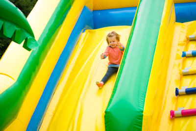 Child sliding down blow up house slide.